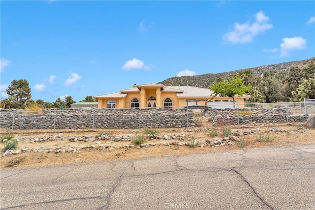 1679 Desert Front Rd, Wrightwood, CA 92397 - view of front facade with a fenced front yard, stucco siding, a garage, and a mountain view