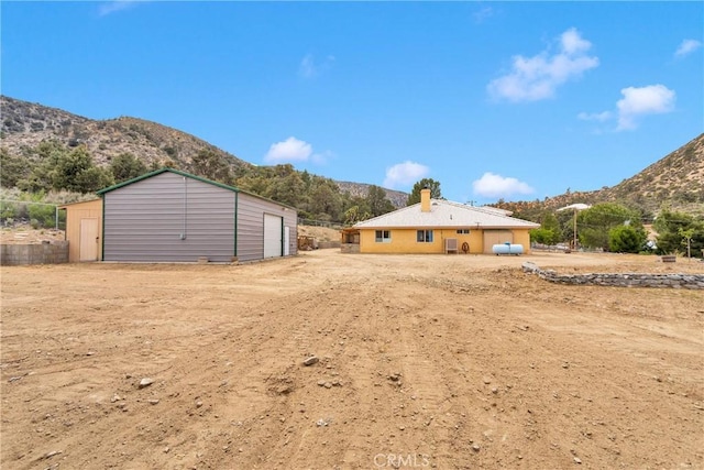 1679 Desert Front Rd, Wrightwood, CA 92397 - back of house featuring a mountain view, a garage, and an outbuilding