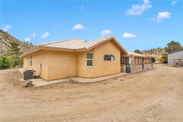 1679 Desert Front Rd, Wrightwood, CA 92397 - back of property featuring stucco siding, central AC unit, a tile roof, and a mountain view