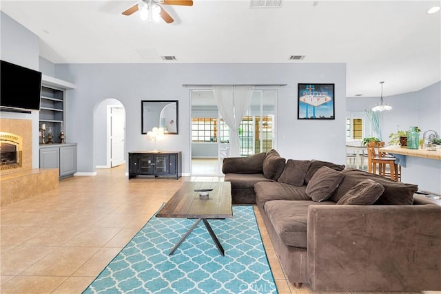 1679 Desert Front Rd, Wrightwood, CA 92397 - living room with arched walkways, built in shelves, a ceiling fan, light tile patterned floors, and a fireplace