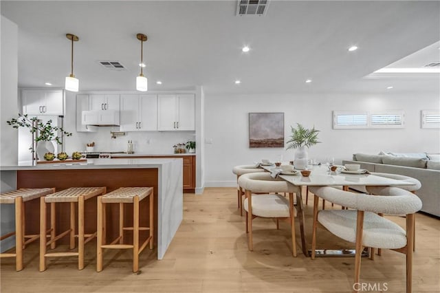 1035 Medford Rd, Pasadena, CA 91107 - kitchen featuring light wood-style floors, a kitchen bar, recessed lighting, white cabinetry, and pendant lighting