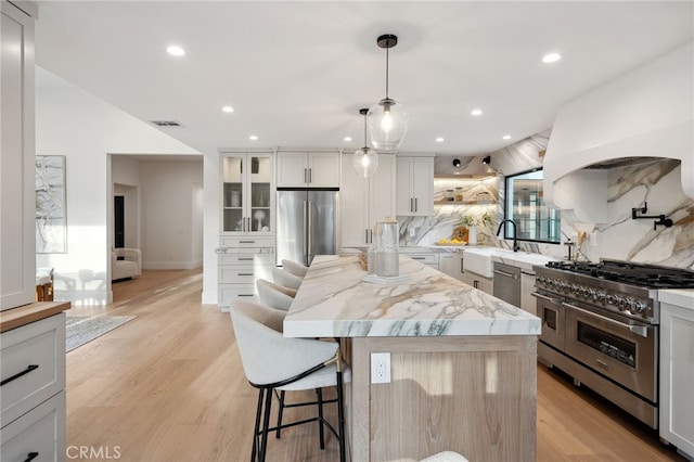 26065 Charing Cross Rd, Valencia, CA 91355 - kitchen featuring appliances with stainless steel finishes, a breakfast bar area, a kitchen island, glass insert cabinets, and recessed lighting