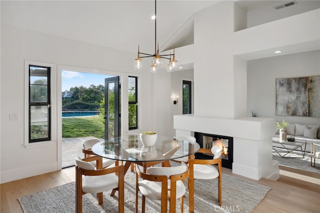 26065 Charing Cross Rd, Valencia, CA 91355 - dining area with light wood-type flooring, a multi sided fireplace, a chandelier, high vaulted ceiling, and recessed lighting
