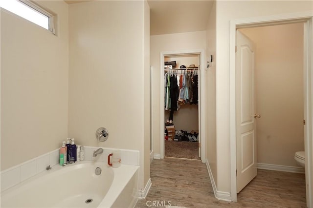 11017 Tipperary Dr, Bakersfield, CA 93311 - bathroom featuring a garden tub, wood finished floors, toilet, and a walk in closet