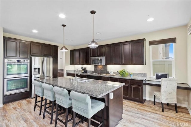 45976 Camino Rubi, Temecula, CA 92592 - kitchen featuring appliances with stainless steel finishes, a sink, dark brown cabinets, stone countertops, and recessed lighting