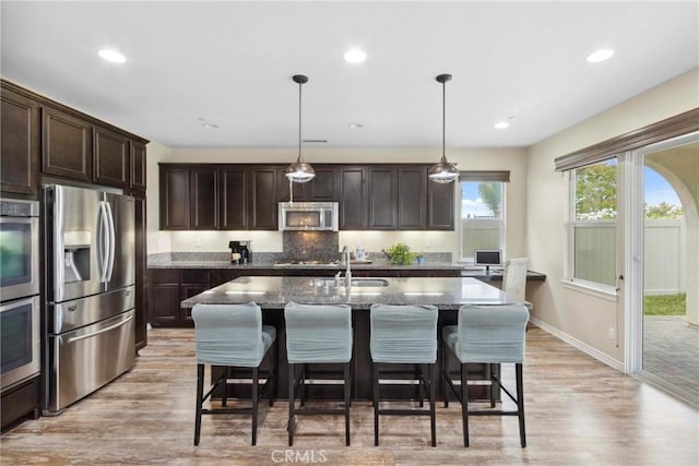 45976 Camino Rubi, Temecula, CA 92592 - kitchen featuring appliances with stainless steel finishes, dark brown cabinets, light wood finished floors, stone counters, and a sink