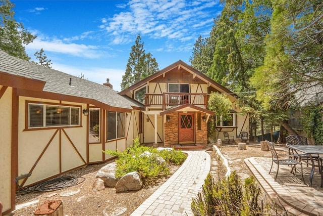1954 Nob Hill Dr, Running Springs, CA 92382 - back of house with a balcony, stucco siding, roof with shingles, and a patio area