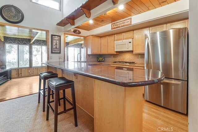 1954 Nob Hill Dr, Running Springs, CA 92382 - kitchen featuring stainless steel appliances, light wood-style floors, light brown cabinetry, backsplash, and a kitchen bar
