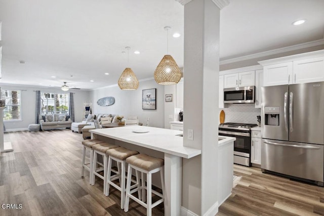 1503 Windshore Way, Oxnard, CA 93035 - kitchen featuring appliances with stainless steel finishes, ornamental molding, white cabinetry, a kitchen breakfast bar, and tasteful backsplash