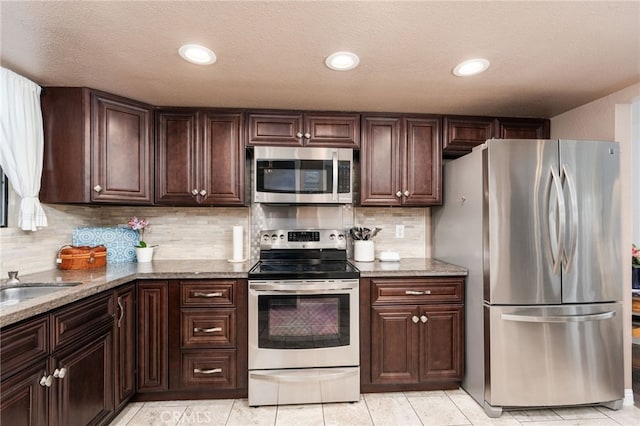 40603 Saddleback Rd, Bass Lake, CA 93604 - kitchen with stainless steel appliances, dark brown cabinetry, light stone counters, decorative backsplash, and light tile patterned flooring