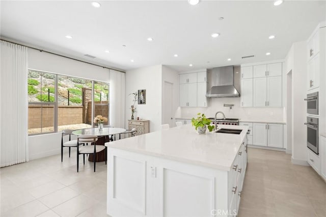 106 Bright Star, Irvine, CA 92618 - kitchen featuring wall chimney range hood, light tile patterned floors, a sink, recessed lighting, and an island with sink