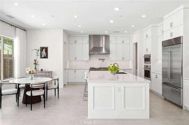 106 Bright Star, Irvine, CA 92618 - kitchen featuring stainless steel built in refrigerator, wall chimney range hood, light countertops, recessed lighting, and a center island with sink