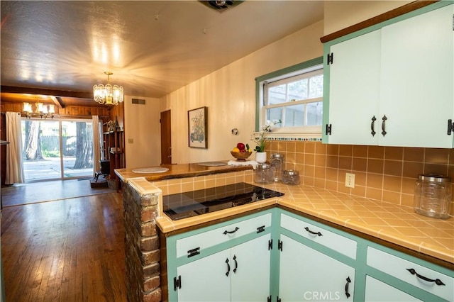 10655 Banner Lava Cap Rd, Nevada City, CA 95959 - kitchen with black electric cooktop, tile counters, a chandelier, a peninsula, and decorative backsplash