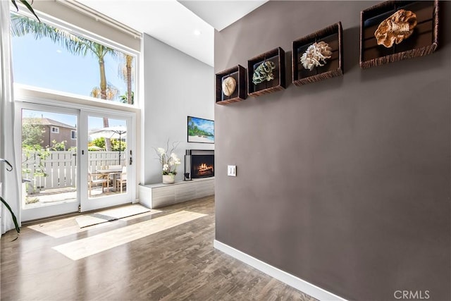 18743 Club Ln, Huntington Beach, CA 92648 - doorway featuring a towering ceiling, a warm lit fireplace, healthy amount of natural light, wood finished floors, and baseboards