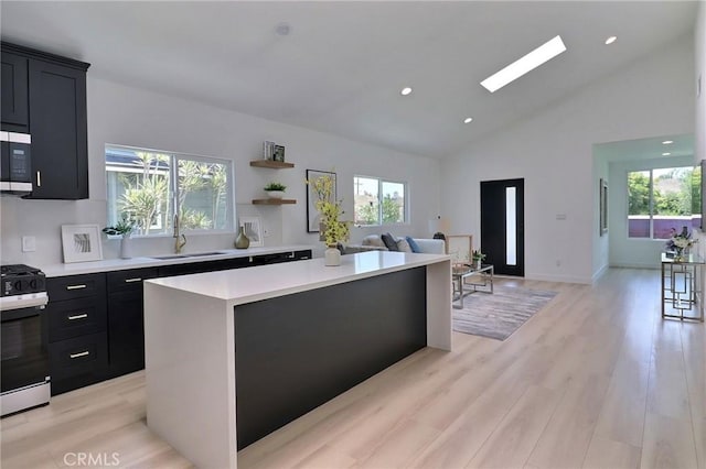 2015 W 42nd Pl, Los Angeles, CA 90062 - kitchen featuring stainless steel appliances, dark cabinetry, a sink, light countertops, and a kitchen island
