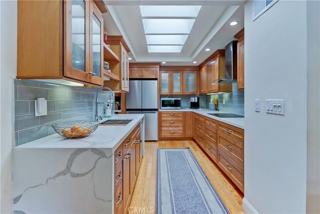 3521 Bahia Blanca W Unit C, Laguna Woods, CA 92637 - kitchen featuring wall chimney range hood, appliances with stainless steel finishes, a sink, light wood-style floors, and tasteful backsplash