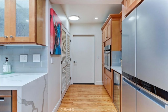 3521 Bahia Blanca W Unit C, Laguna Woods, CA 92637 - kitchen with stainless steel appliances, light wood finished floors, decorative backsplash, light stone countertops, and baseboards