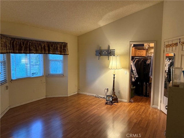 1808 Via Entrada, Rowland Heights, CA 91748 - unfurnished bedroom featuring wood finished floors, a textured ceiling, vaulted ceiling, a spacious closet, and baseboards