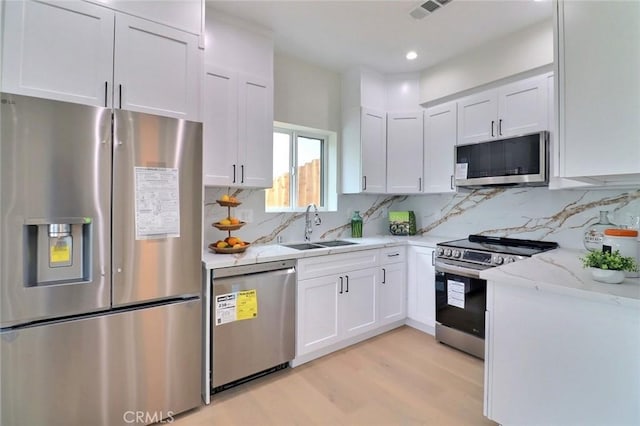 4850 Buchanan, Los Angeles, CA 90042 - kitchen featuring stainless steel appliances, a sink, light wood-type flooring, white cabinets, and light stone countertops