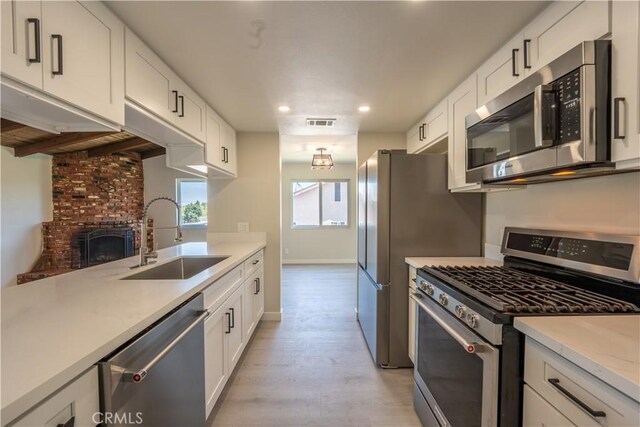5187 Cedar St, Jurupa Valley, CA 92509 - kitchen with stainless steel appliances, light wood-style flooring, recessed lighting, white cabinets, and a brick fireplace