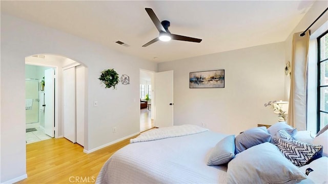8535 Creekside Pl, Rancho Cucamonga, CA 91730 - bedroom featuring arched walkways, light wood finished floors, ensuite bathroom, baseboards, and a ceiling fan