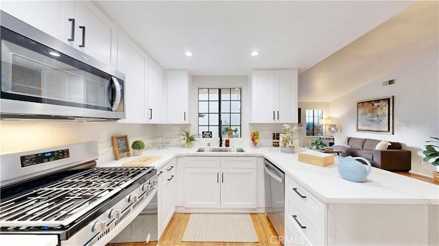 8535 Creekside Pl, Rancho Cucamonga, CA 91730 - kitchen featuring appliances with stainless steel finishes, a peninsula, light wood-style floors, white cabinetry, and open floor plan