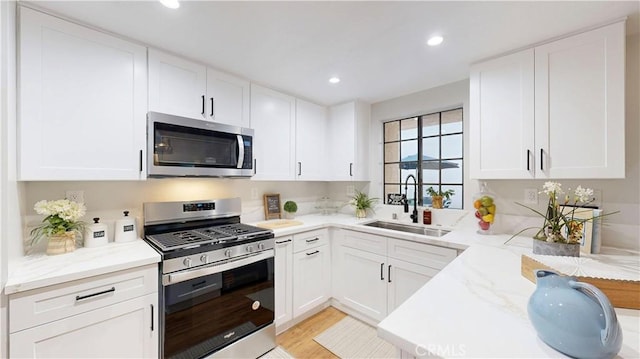 8535 Creekside Pl, Rancho Cucamonga, CA 91730 - kitchen with appliances with stainless steel finishes, a sink, white cabinetry, light stone counters, and recessed lighting