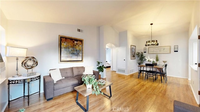 8535 Creekside Pl, Rancho Cucamonga, CA 91730 - living area featuring vaulted ceiling, a chandelier, light wood finished floors, arched walkways, and baseboards