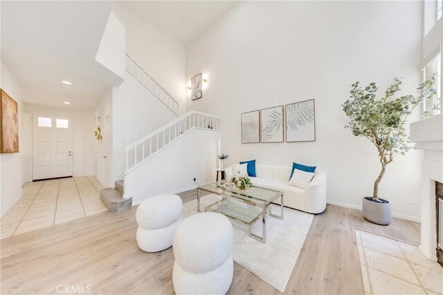 13445 Savanna, Tustin, CA 92782 - living room featuring stairs, wood finished floors, a fireplace with flush hearth, a high ceiling, and baseboards