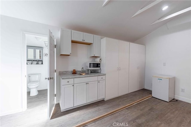 4408 Walnut Ave, Simi Valley, CA 93063 - kitchen with white microwave, a sink, light wood-type flooring, light countertops, and lofted ceiling