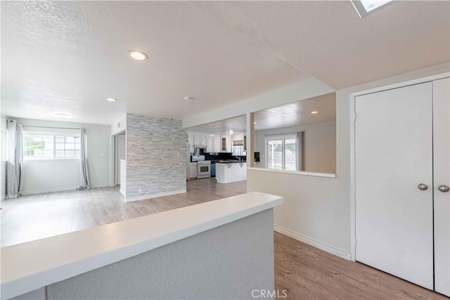 4408 Walnut Ave, Simi Valley, CA 93063 - kitchen with light wood-style floors, open floor plan, stainless steel range oven, white cabinetry, and plenty of natural light