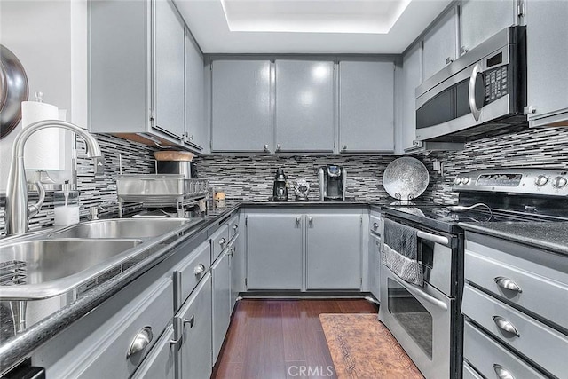 44 Carriage Way Unit 108, Pomona, CA 91766 - kitchen featuring stainless steel appliances, a sink, dark countertops, gray cabinetry, and decorative backsplash
