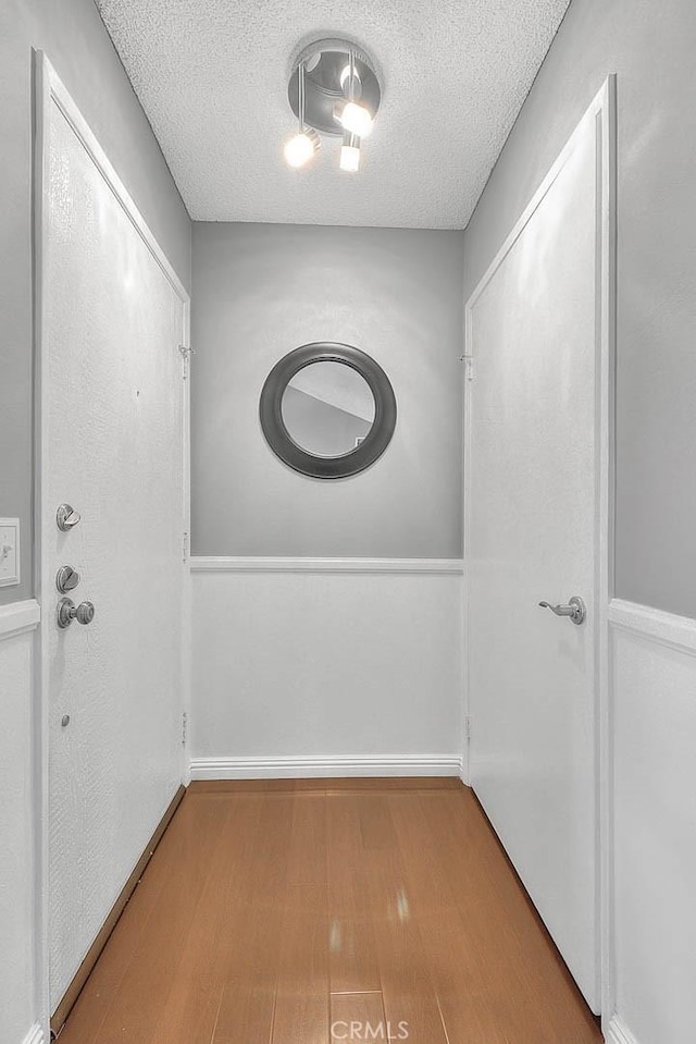 44 Carriage Way Unit 108, Pomona, CA 91766 - doorway with a textured ceiling, wood finished floors, and baseboards