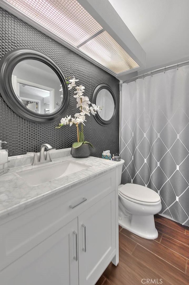 44 Carriage Way Unit 108, Pomona, CA 91766 - bathroom with vanity, toilet, wood finished floors, and a shower with shower curtain