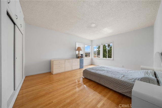 2917 W Hellman Ave, Alhambra, CA 91803 - bedroom featuring light wood-style flooring, a textured ceiling, a closet, and baseboards