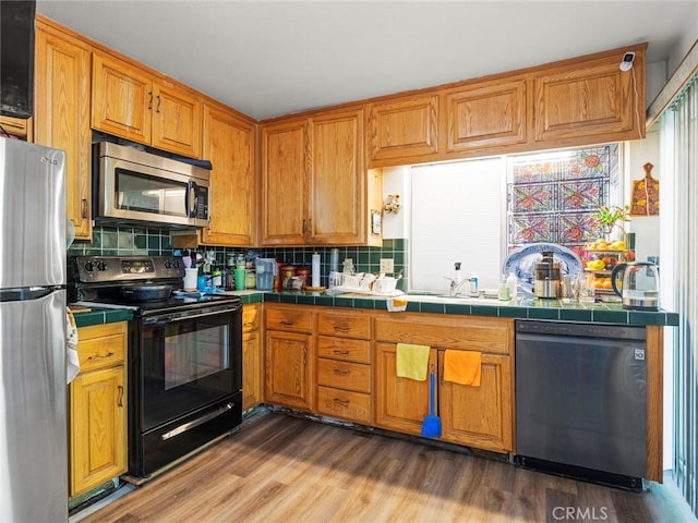 3038 Blakeman Ave, Rowland Heights, CA 91748 - kitchen featuring appliances with stainless steel finishes, tile countertops, backsplash, brown cabinets, and wood finished floors