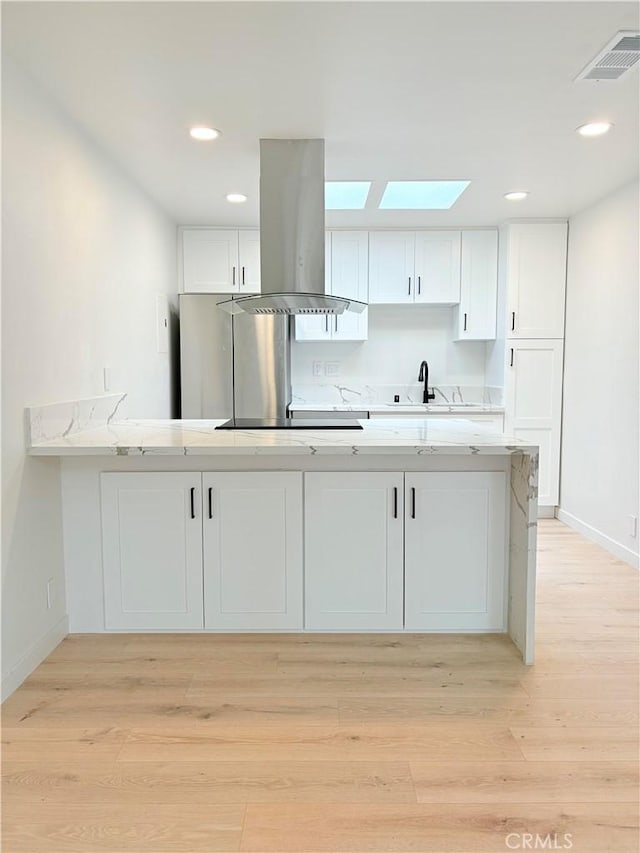 3088 Via Serena N Unit D, Laguna Woods, CA 92637 - kitchen featuring island range hood, white cabinets, a skylight, light countertops, and a sink