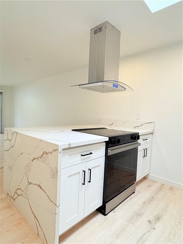 3088 Via Serena N Unit D, Laguna Woods, CA 92637 - kitchen featuring island exhaust hood, black / electric stove, light wood finished floors, and light stone counters