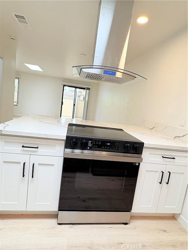 3088 Via Serena N Unit D, Laguna Woods, CA 92637 - kitchen featuring electric stove, island range hood, light stone counters, and healthy amount of natural light
