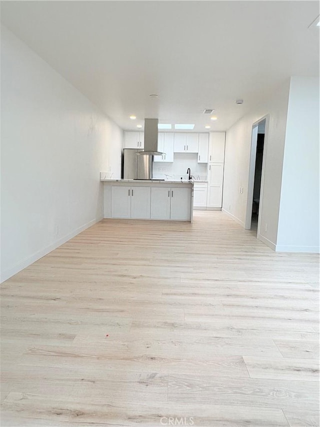 3088 Via Serena N Unit D, Laguna Woods, CA 92637 - kitchen featuring open floor plan, light wood-style floors, island range hood, white cabinetry, and baseboards