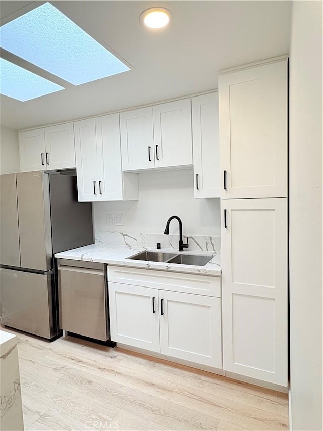 3088 Via Serena N Unit D, Laguna Woods, CA 92637 - kitchen featuring appliances with stainless steel finishes, a skylight, a sink, white cabinetry, and light wood-style floors