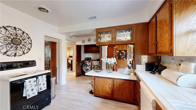 13424 Washington Ave, Hawthorne, CA 90250 - kitchen featuring electric stove, independent washer and dryer, brown cabinets, a peninsula, and tile countertops