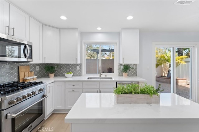 7 Monticello Ln, Rancho Santa Margarita, CA 92688 - kitchen featuring stainless steel appliances, a sink, white cabinetry, tasteful backsplash, and a kitchen island