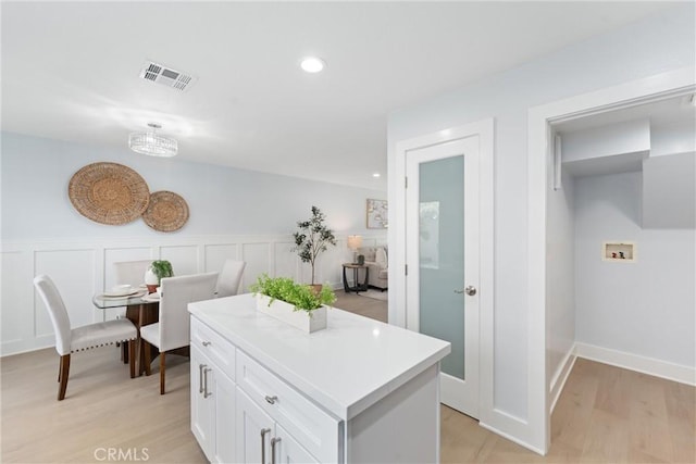 7 Monticello Ln, Rancho Santa Margarita, CA 92688 - kitchen featuring white cabinets, light wood-type flooring, light countertops, recessed lighting, and wainscoting