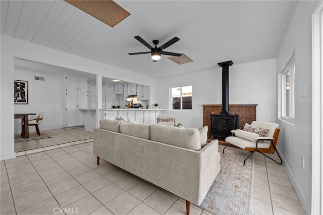 1086 Amacayo Ct, San Diego, CA 92154 - living room featuring light tile patterned floors, a wood stove, ceiling fan, and wood ceiling