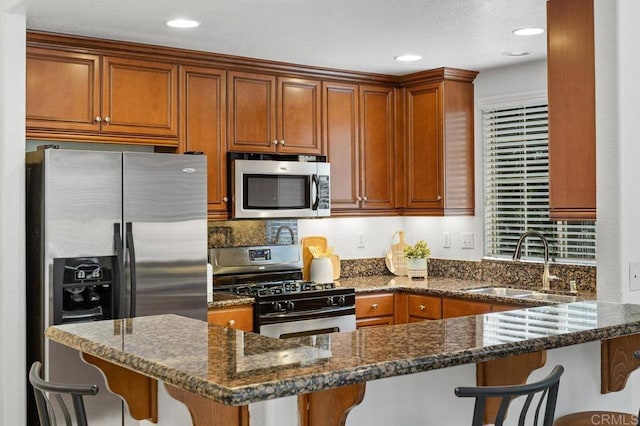 5529 Old Ranch Rd Unit 47, Oceanside, CA 92057 - kitchen featuring appliances with stainless steel finishes, a sink, a kitchen bar, dark stone counters, and brown cabinetry