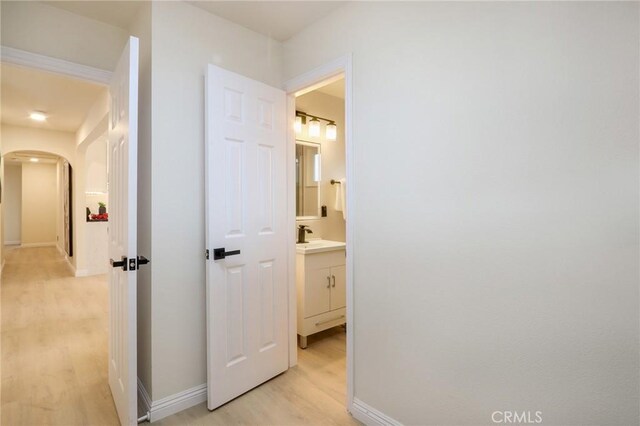 18479 Aguiro St, Rowland Heights, CA 91748 - hallway with light wood-style flooring, arched walkways, baseboards, and a sink