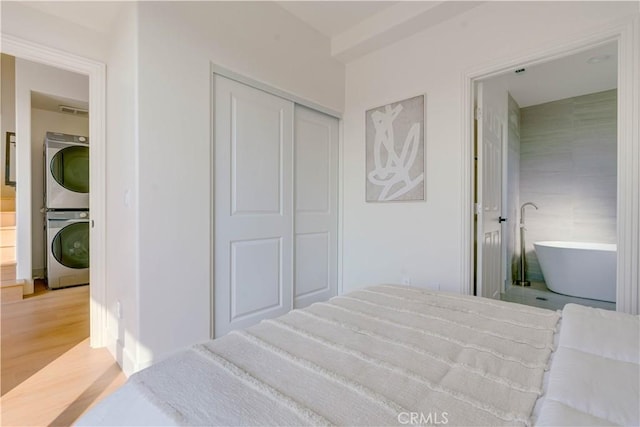 712 N Chestnut Ave, Los Angeles, CA 90042 - bedroom featuring stacked washer / drying machine, light wood-style floors, and a closet