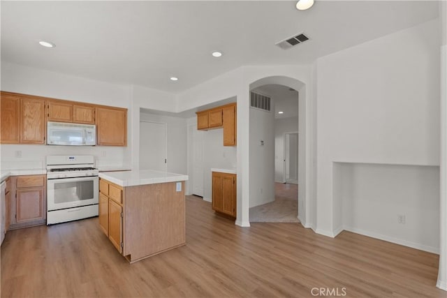4349 Bethpage Dr, Palmdale, CA 93551 - kitchen with white appliances, arched walkways, light wood-type flooring, a center island, and recessed lighting