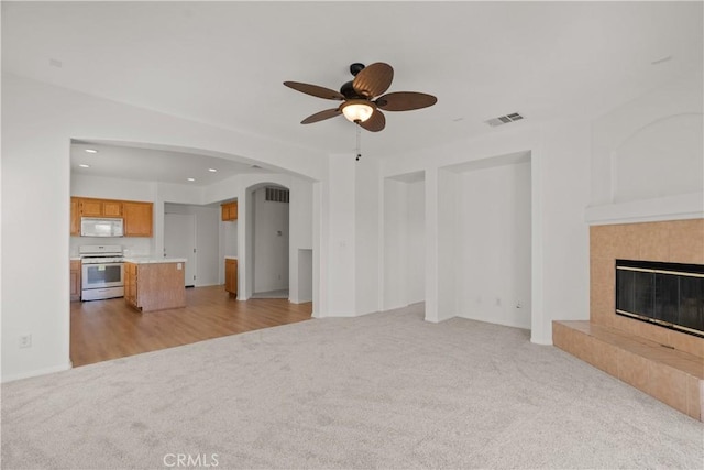 4349 Bethpage Dr, Palmdale, CA 93551 - unfurnished living room featuring light carpet, a ceiling fan, arched walkways, a tiled fireplace, and recessed lighting